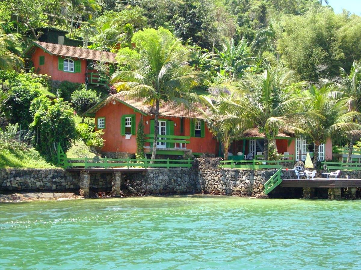 A casa vista do mar, com o deck e a vegetação da Ilha da Caieira ao fundo